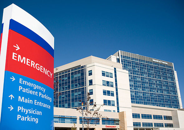 modern hospital with emergency sign and multi-story glass facade
